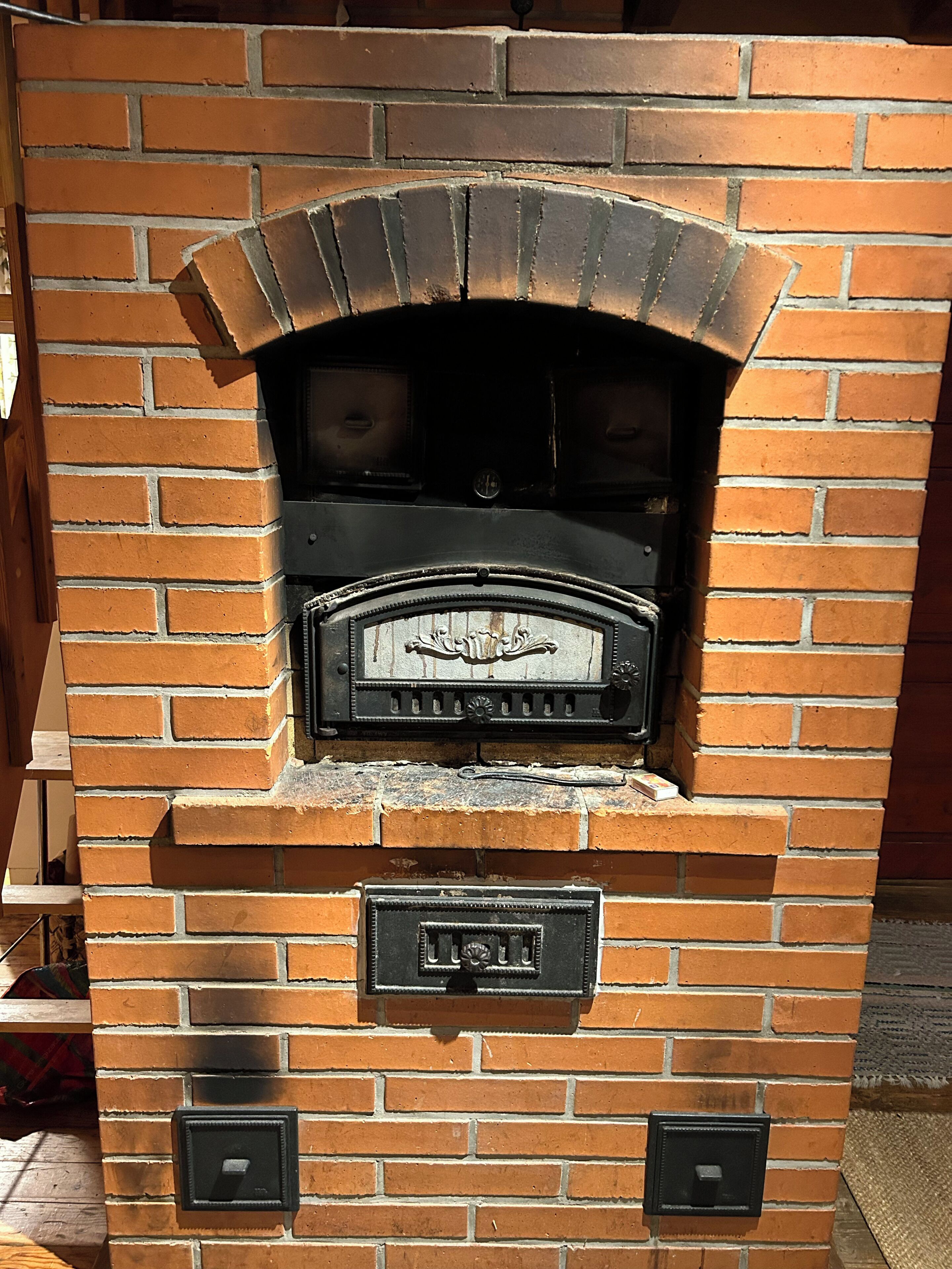 Un four extérieur en briques, doté d’une façade en métal décorative, de deux ouvertures latérales et d’une poignée en métal.