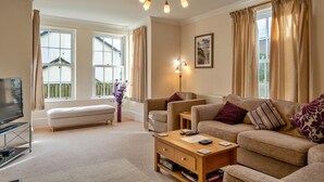 A living room with a sofa, a coffee table, a TV, and a lamp. - St David's Country House (Woodford)