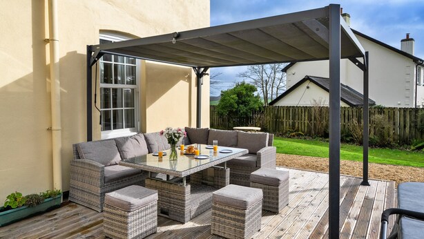 An outdoor patio with a glass-top table, wicker furniture, and a pergola. - St David's Country House (Woodford)