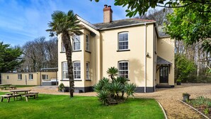 A two-story building with a garden patio, a palm tree, and a brick chimney. - St David's Country House (Woodford)