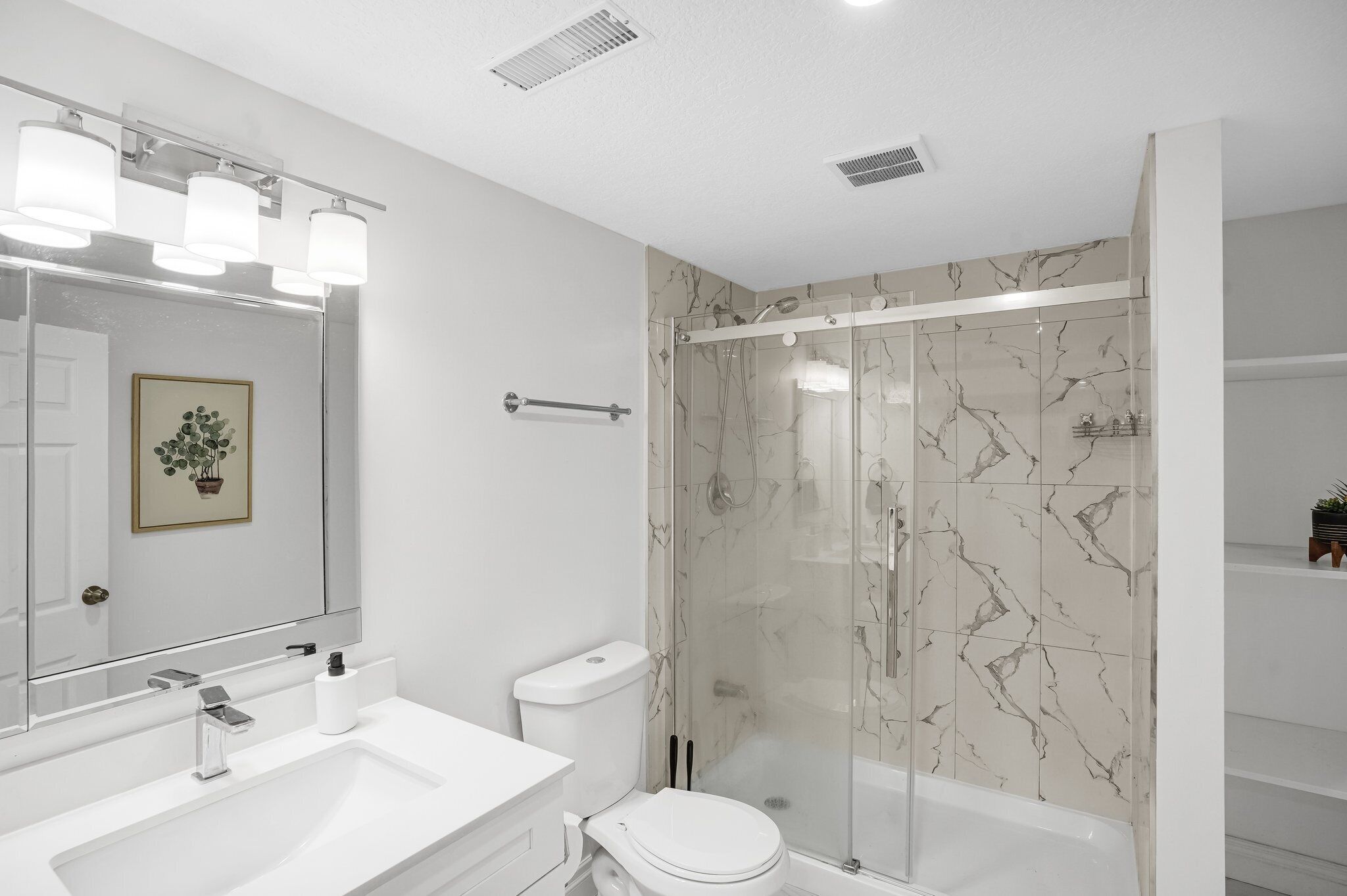 Un baño con lavamanos, inodoro y ducha con puertas de vidrio.