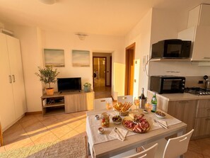 A modern kitchen with a dining area, a TV, and a microwave. - Voiandes balcony apartment garden and pool (Tremosine)