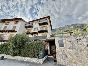 A multi-story building with balconies, stone walls, and a mountainous backdrop. - Voiandes balcony apartment garden and pool (Tremosine)