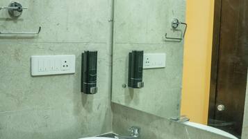 A bathroom with a white sink, marble walls, a mirror, and a door leading to another room.