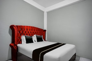 A bed with a tufted headboard, white bedding, and a black and white striped bedspread. - Spacious Deluxe Double Near Ring Road City Walks (Medan)