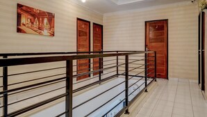 A hotel interior with a staircase, wooden doors, and a painting on the wall.