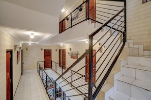 Ein mehrgeschossiges Interieur mit einer Treppe, weiß gefliesten Wänden und Holztüren.