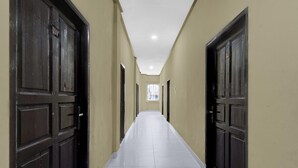 A long, narrow hallway with dark wooden doors on both sides and a tiled floor. - Spacious Deluxe Double Near Mall Ciputra (Pekanbaru)