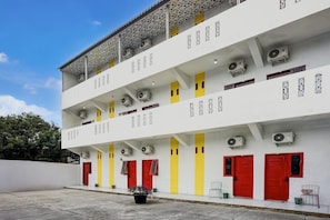 A multi-story building with air conditioning units, red doors, and a white facade.