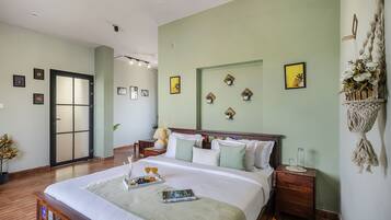 A hotel room with a bed, bedside tables, a nightstand, a door, and wall decorations.