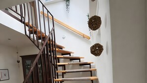 Una escalera con escalones de madera y barandillas de metal, que sube a un piso superior.