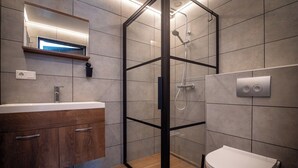 Ein modernes Badezimmer mit einer Duschkabine aus Glas, einem hölzernen Waschtisch und einer Toilette.