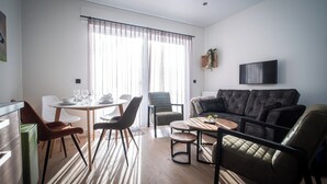 Ein modernes Wohnzimmer mit Sofa, Esstisch, Stühlen und Fernseher.