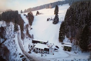 Ein schneebedecktes Skigebiet mit Hauptlodge, Parkplatz und Seilbahnen.