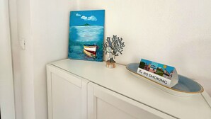 A painting of a boat on water, a metal sculpture, and a 'NO SMOKING' sign on a table. - Schiappacasse 11 (Rapallo)