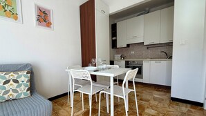 A compact living space with a dining area, kitchenette, and a sofa with patterned cushions. - Schiappacasse 11 (Rapallo)
