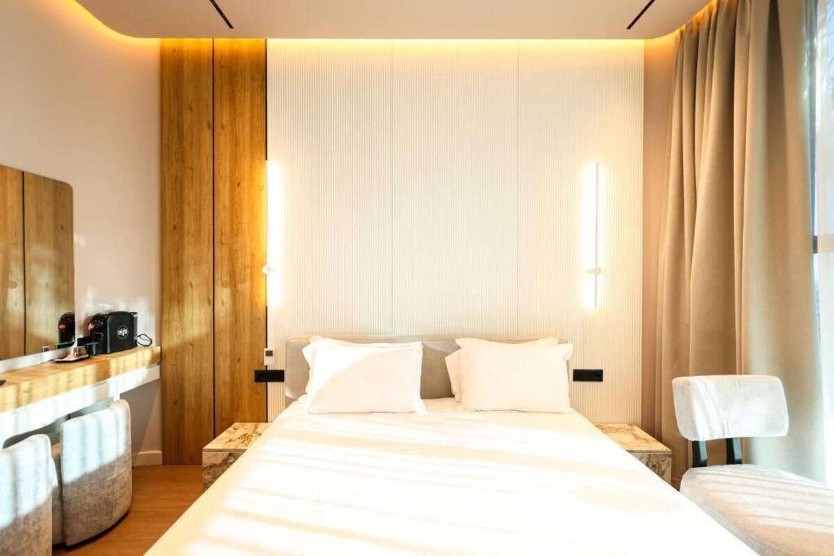 Una habitación de hotel con cama, mesitas de noche, escritorio y una silla.