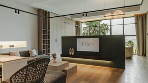A modern interior with a sofa, a chair, a desk, a large window, and a wall-mounted sign. - Zins Luxury Apartments (Durrës)