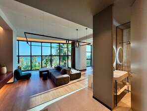 A modern interior with a large window, a seating area, and a bathroom. - Zins Luxury Apartments (Durrës)