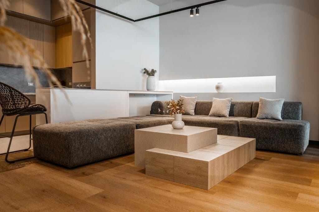 A modern living room with a sectional sofa, a coffee table, and a dining area with a chair.