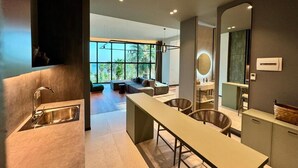 A modern kitchen with a built-in sink, a dining area with a long table, and a large window providing natural light. - Zins Luxury Apartments (Durrës)