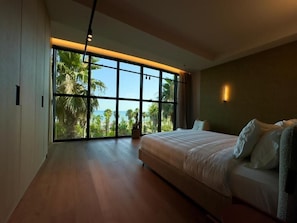 A modern bedroom with a large window, a bed, and a wooden floor. - Zins Luxury Apartments (Durrës)