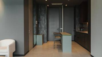 A modern kitchen with dark cabinetry, a small island, and a white chair.