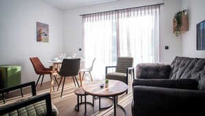 En moderne stue med sofa, stole, sofabord og et spiseområde med bord og stole.