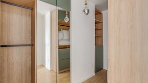 Ein Zimmer mit Holzboden, einem grünen Schrank, einer weißen Wand und einer hängenden Leuchte.