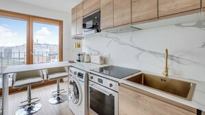 Eine moderne Küche mit Einbau-Mikrowelle, Backofen und Spüle, einer Waschmaschine sowie einer Bar mit Hockern.