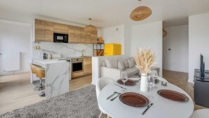 Eine moderne Küche mit Holzschränken, einem gelben Kühlschrank und einer Essecke mit einem für zwei Personen gedeckten Tisch.