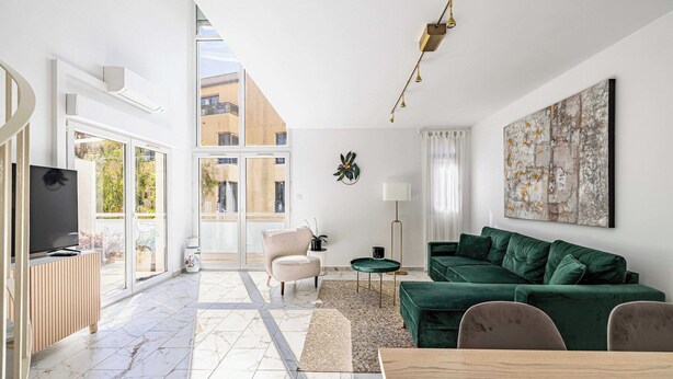 Un salon moderne avec un canapé vert, un téléviseur et un coin repas.