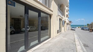 A hotel with large glass doors, a visible parking area, and a view of the sea. - Levante Eight Sea View Holiday Home with Sea View, Wi-Fi, and Air Conditioning (Bari)