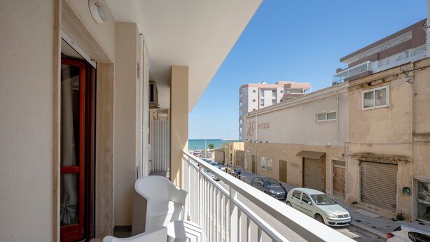 A balcony with a view of a street, a building with a cinema sign, and parked cars. - Levante Eight Sea View Holiday Home with Sea View, Wi-Fi, and Air Conditioning (Bari)