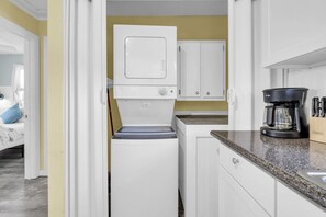 A compact kitchen with a white refrigerator, a coffee maker, and a countertop. - Sandy Toes Hideaway- Multi Family! (Panama City)