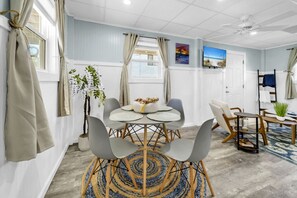 A modern room with a round table, grey chairs, a small plant, and a TV on the wall. - Sandy Toes Hideaway- Multi Family! (Panama City)