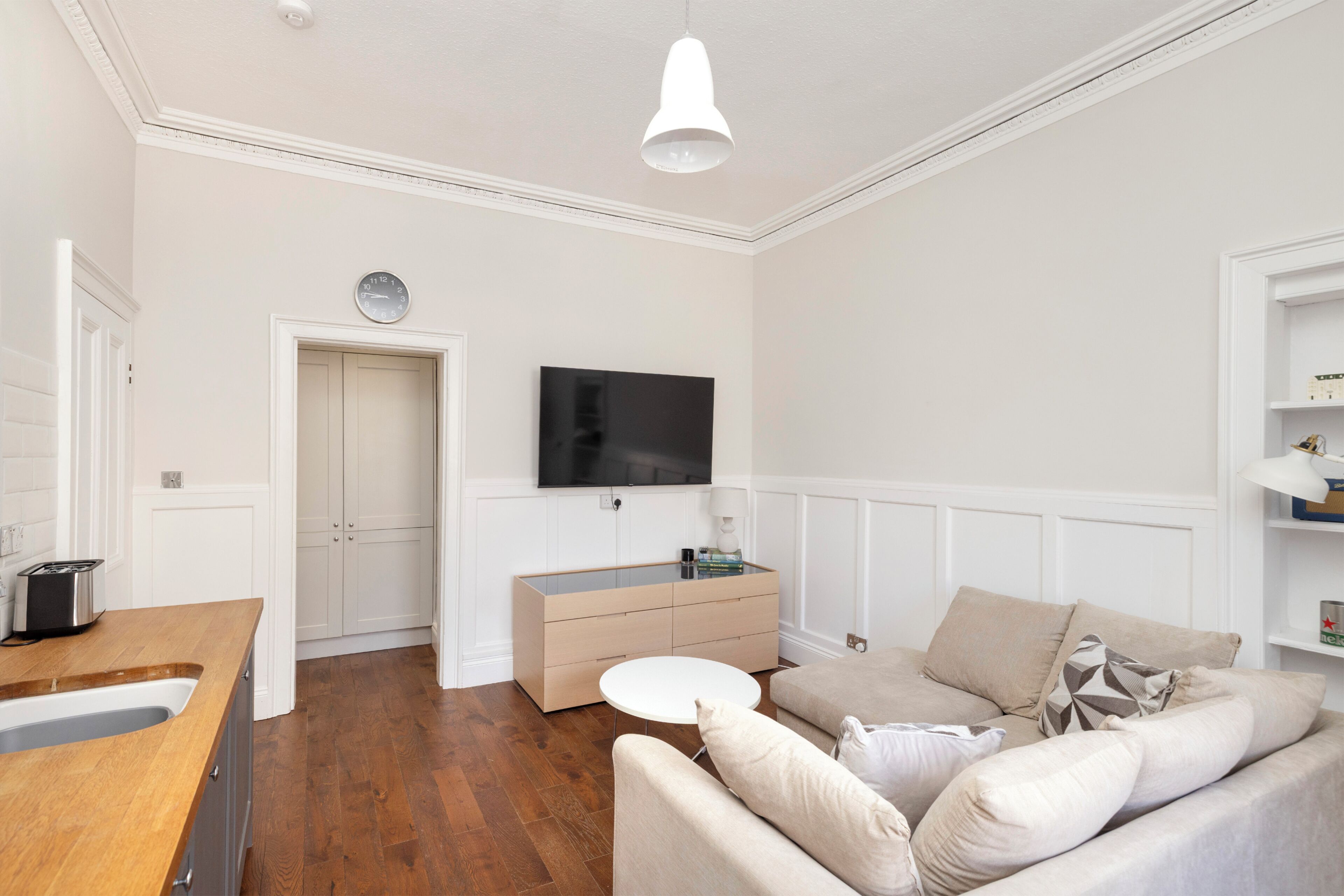 Una sala de estar moderna con un televisor de pantalla plana, un sofá, una mesa de centro y una encimera de cocina de madera.