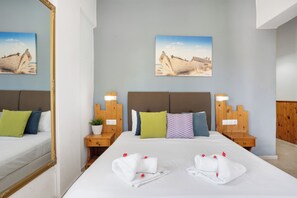 A hotel room with a bed, two nightstands, a mirror, and two paintings on the wall. - malia boutique studios (Malia)