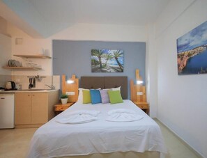 Ein Schlafzimmer mit einem Bett, Kissen, Nachttischen, einem Gemälde und Meerblick.