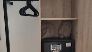A wooden wardrobe with a hanging rod and a black electronic device on one of the shelves. - malia boutique studios (Malia)