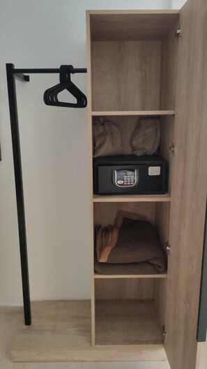 Un armario de madera con barra para colgar y un dispositivo electrónico negro sobre una de sus estantes.