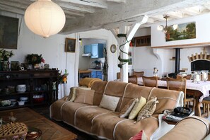 Ein gemütliches Wohnzimmer mit braunem Sofa, Holzmöbeln und einem Essbereich mit Tisch und Stühlen.