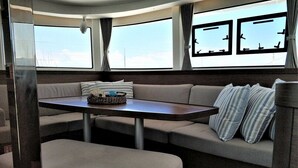 Een gezellig RV-interieur met een eettafel, beklede zitplaatsen en grote ramen.