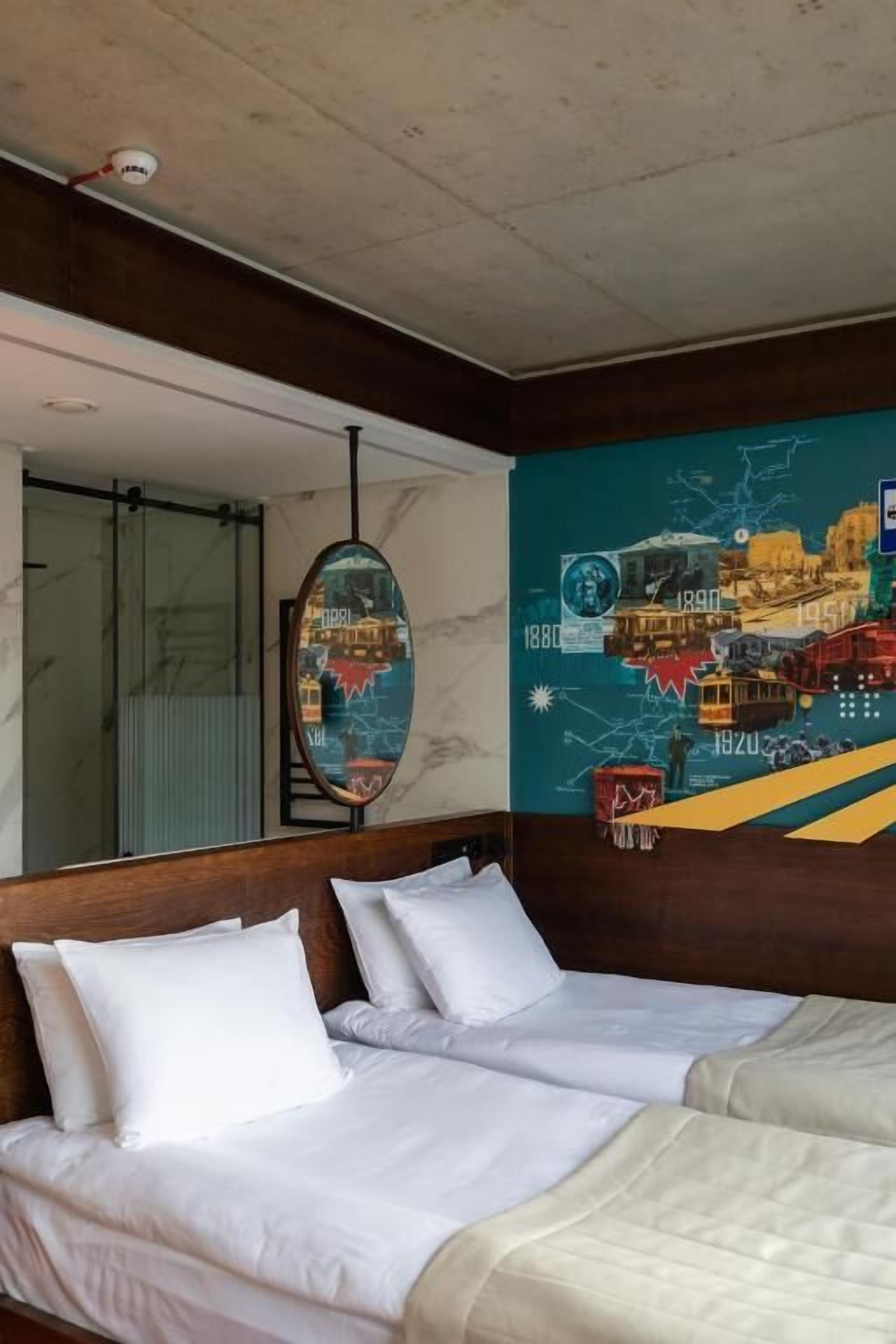 A hotel room with a large bed, a mirror, and a wall mural.
