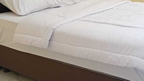 Een bed met hoofdbord, kussens en dekbed.