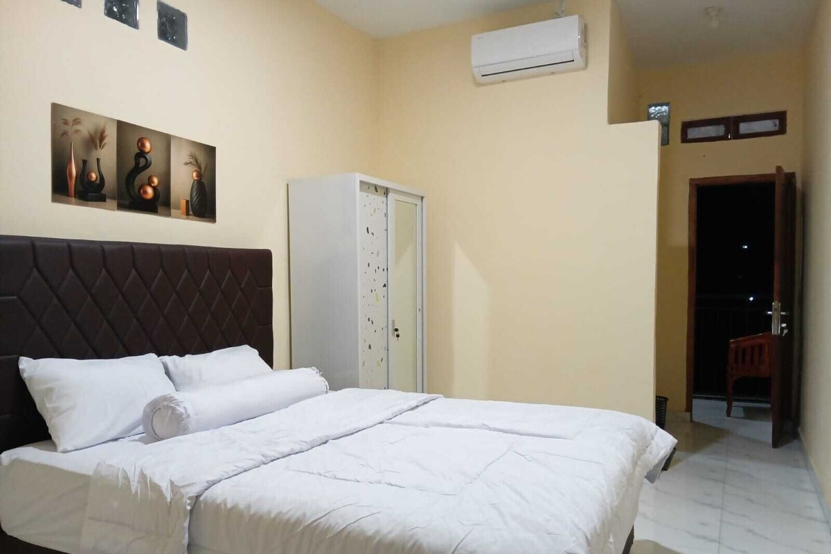 A hotel room with a bed, a wardrobe, and an air conditioning unit.