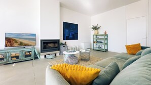 Un salon moderne avec une cheminée, un téléviseur, une bibliothèque et un canapé.