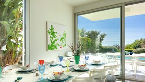 Un coin repas avec une table dressée pour quatre personnes, de grandes fenêtres et une vue sur l’extérieur.