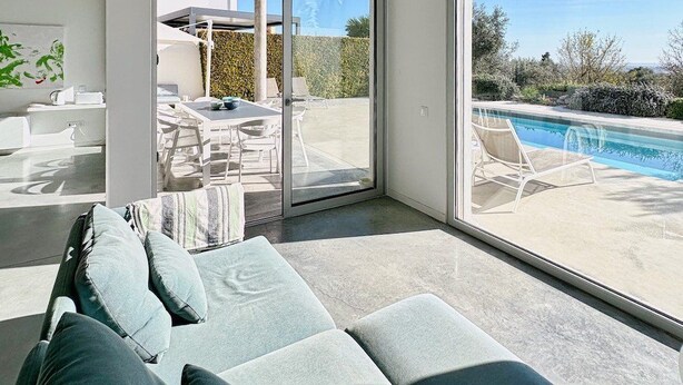 Un salon moderne comprenant un canapé, un coin repas et donnant sur une piscine.