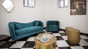 Ein Zimmer mit taubenfarbenen Sofas, einem goldfarbenen Couchtisch und einem Schachbrettmuster-Boden.